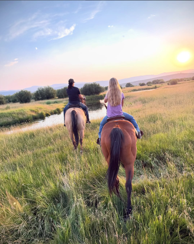 Horseback riders crossing a meadow near Star Valley & Jackson, Wyoming at sunset
