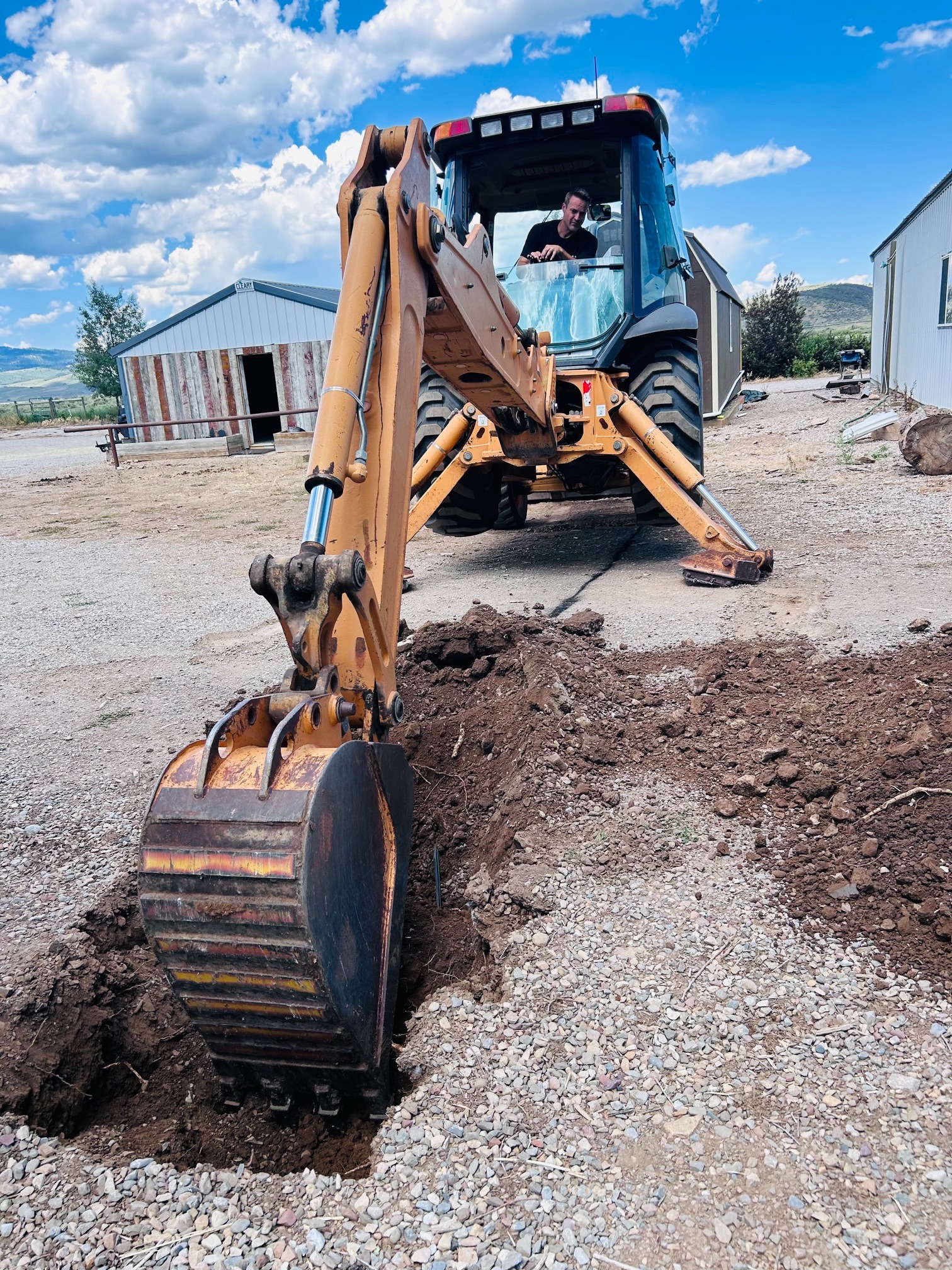 Wyoming Peak team member operating a backhoe on a ranch project